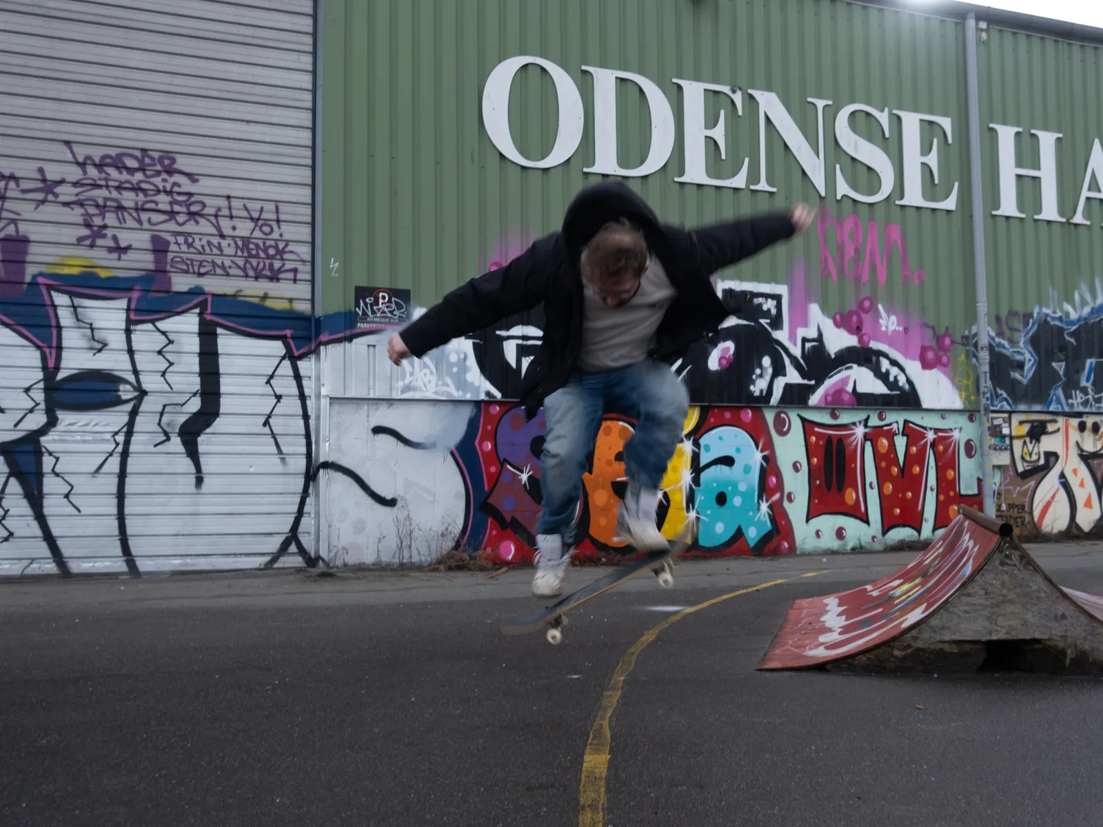 Skater i luften foran en grafittivæg ved Odense Havn